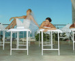 Four women on massage tables, one laughing wearing bridal veil