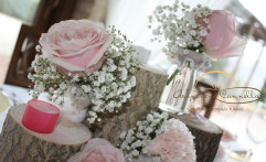 Dettaglio centrotavola con tronchi e fiori e candele tenui.